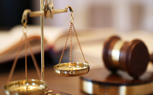 The Scales of Justice with a gavel in the background